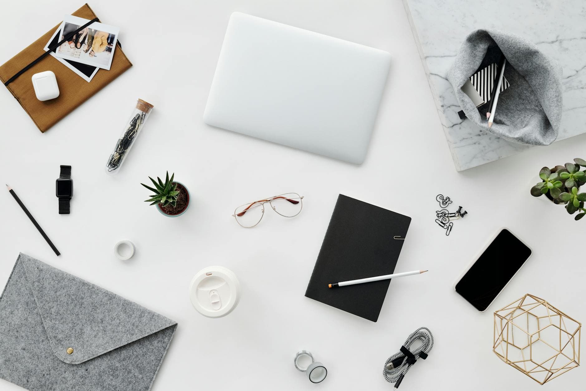 An overhead flat-lay of a desk with a laptop, headphones, and notebook