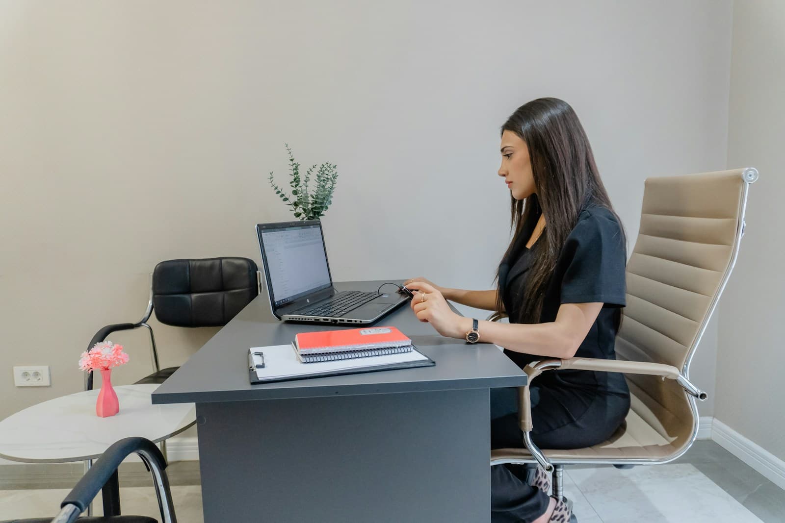 A person at a wooden desk using a laptop in a tidy workspace