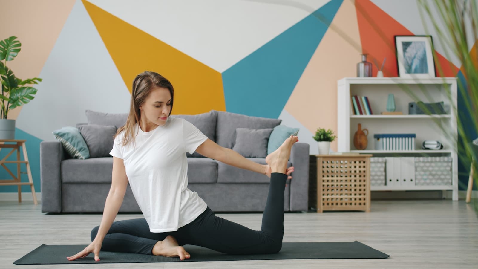 A person doing a seated yoga stretch on a mat in a sunlit living room