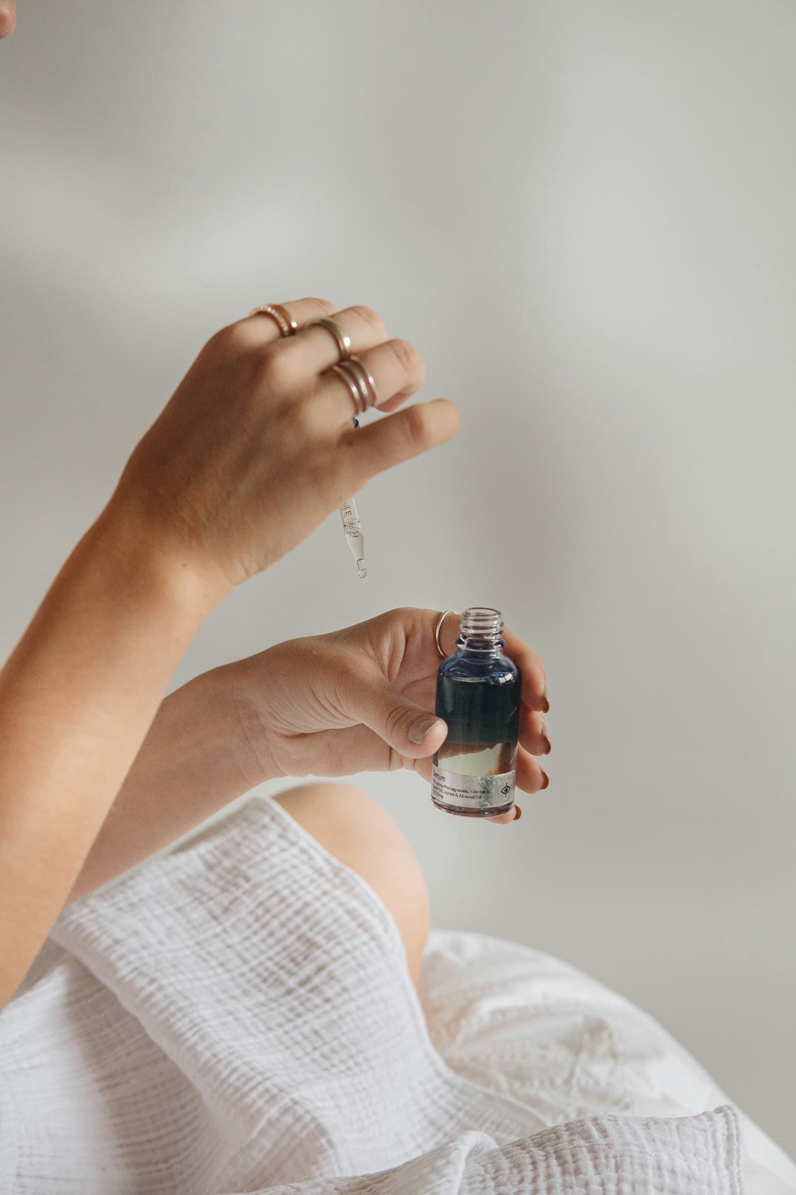Hands holding a small dropper bottle of skincare oil
