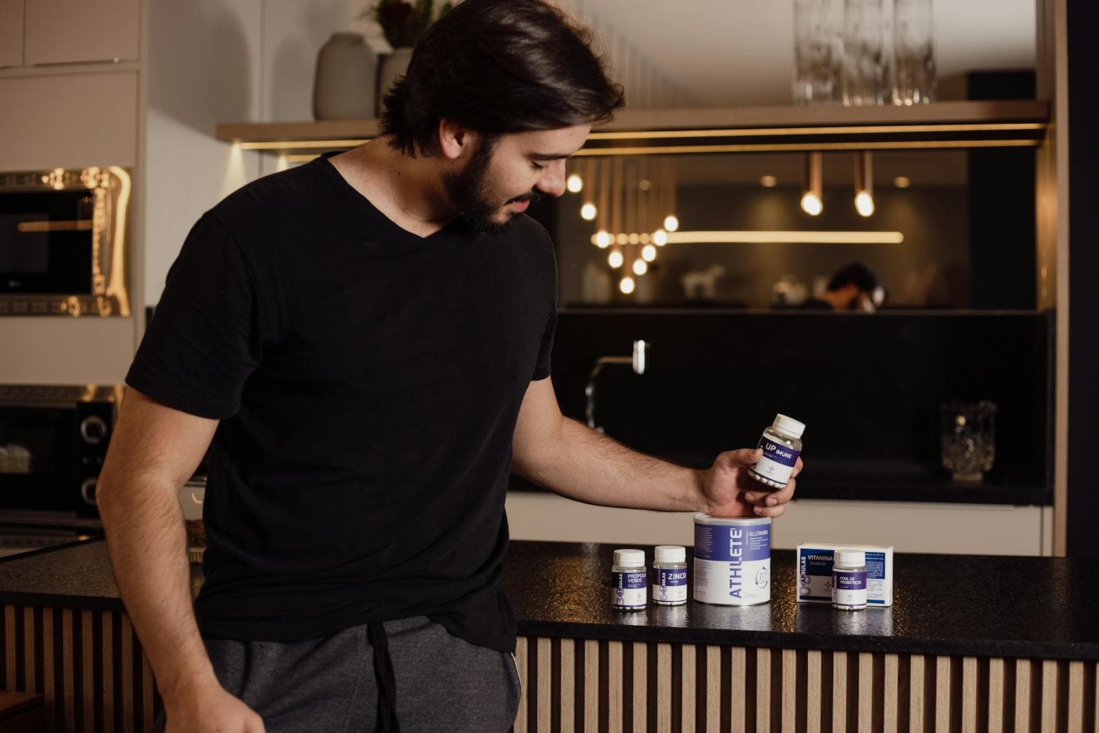 A man examining a row of supplement bottles in a modern kitchen