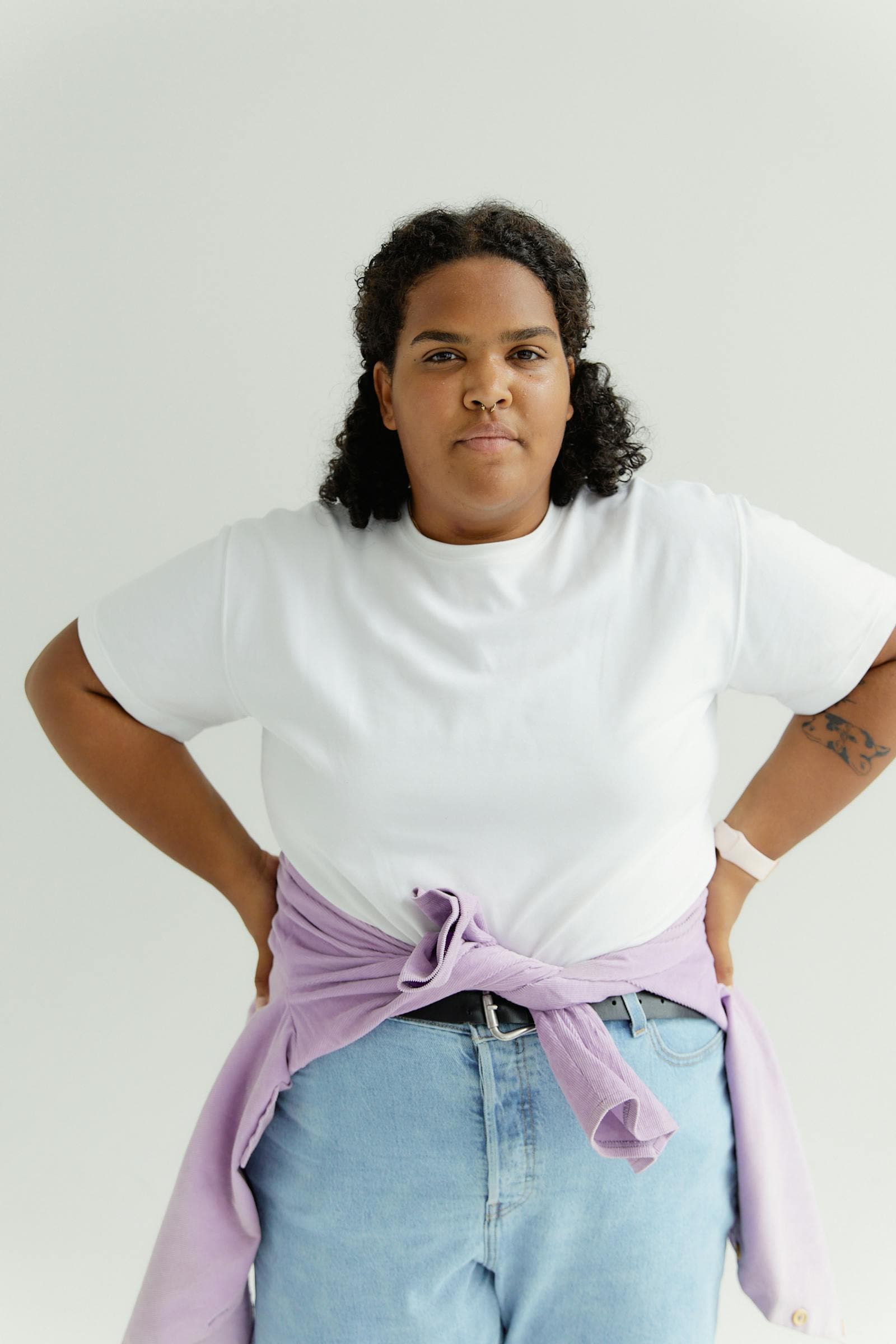 A confident woman in a white t-shirt, hands on her hips, studio portrait