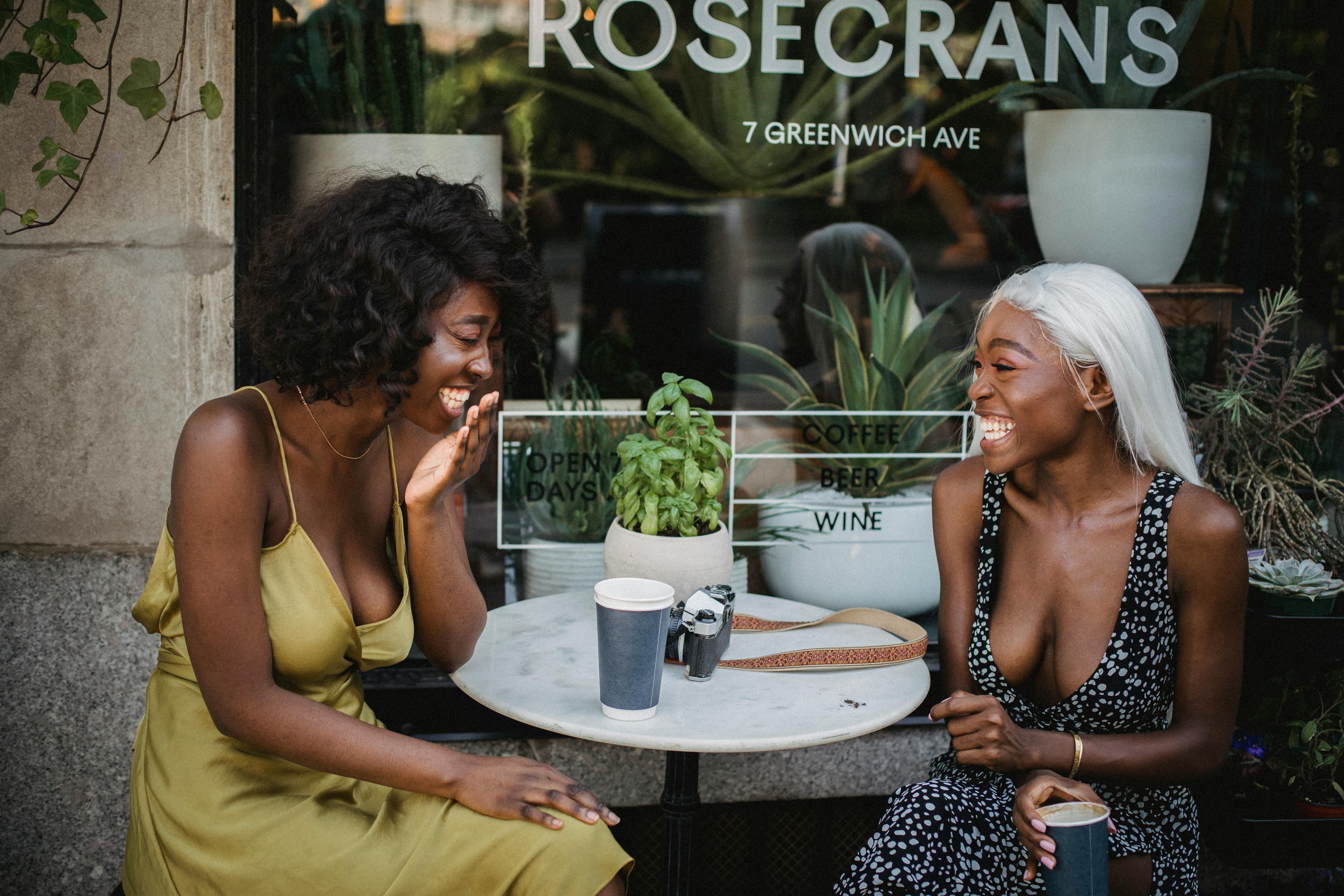 Friends laughing together at a café table in daylight