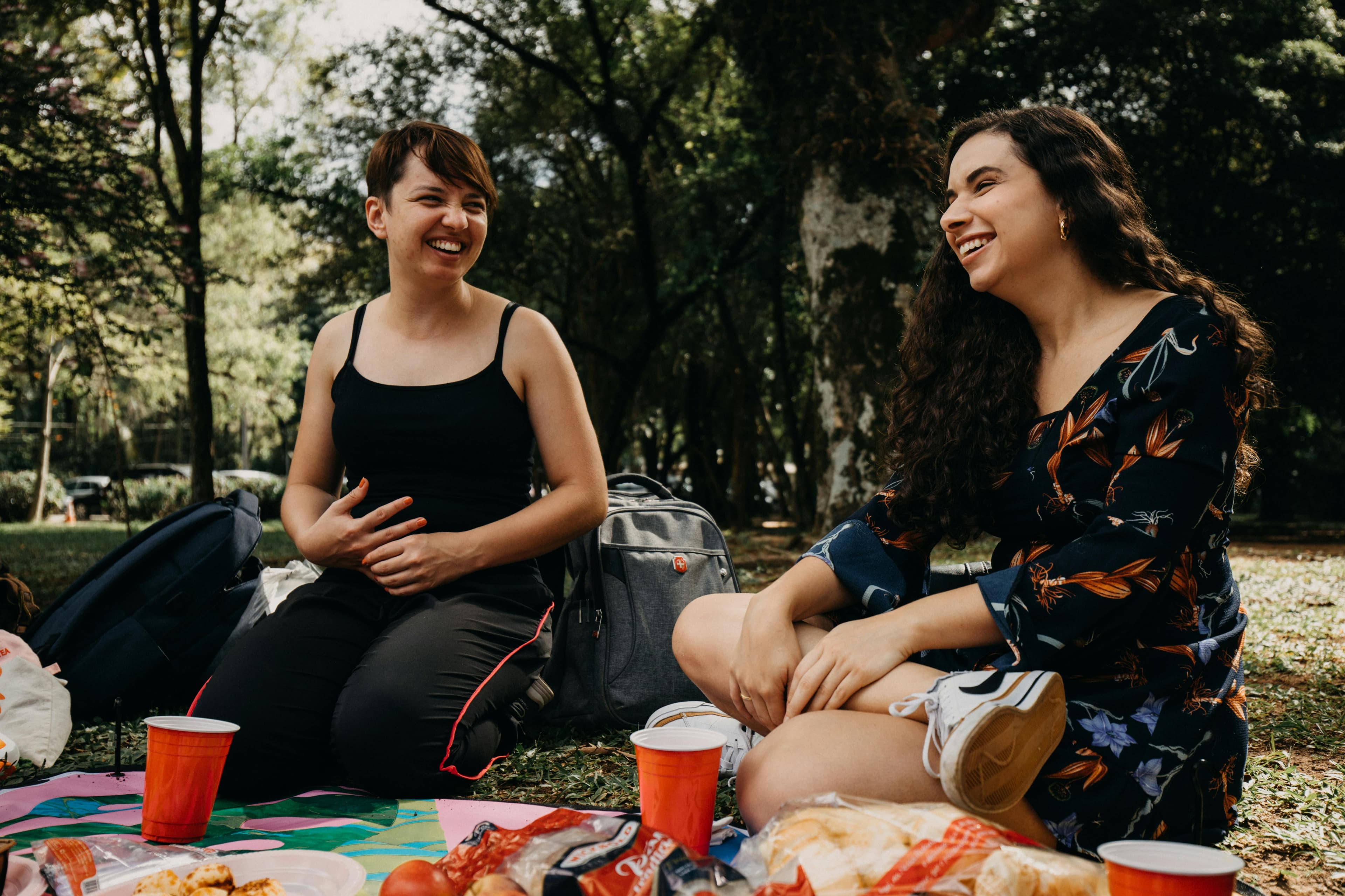 A small group sharing food on a blanket in a park