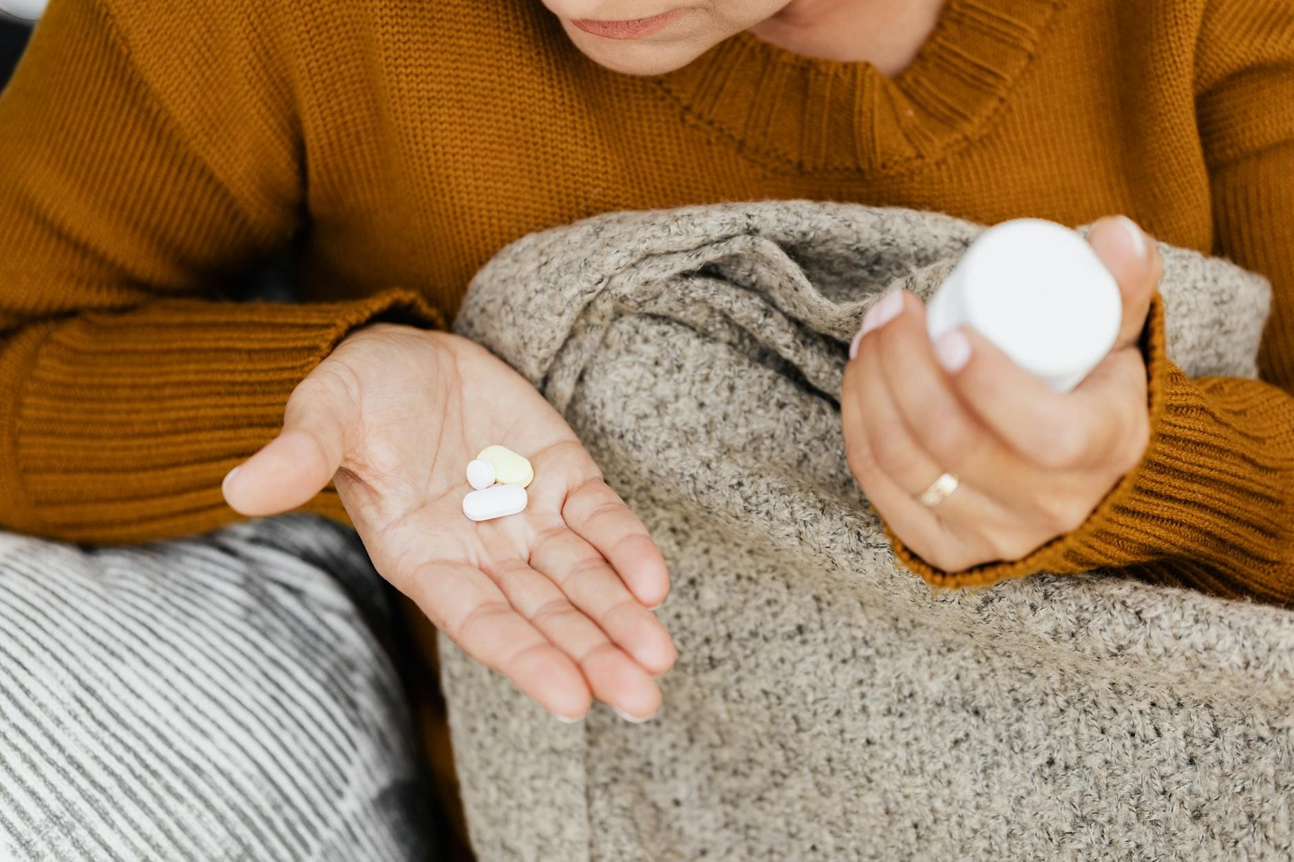 A woman holding morning vitamins in a kitchen